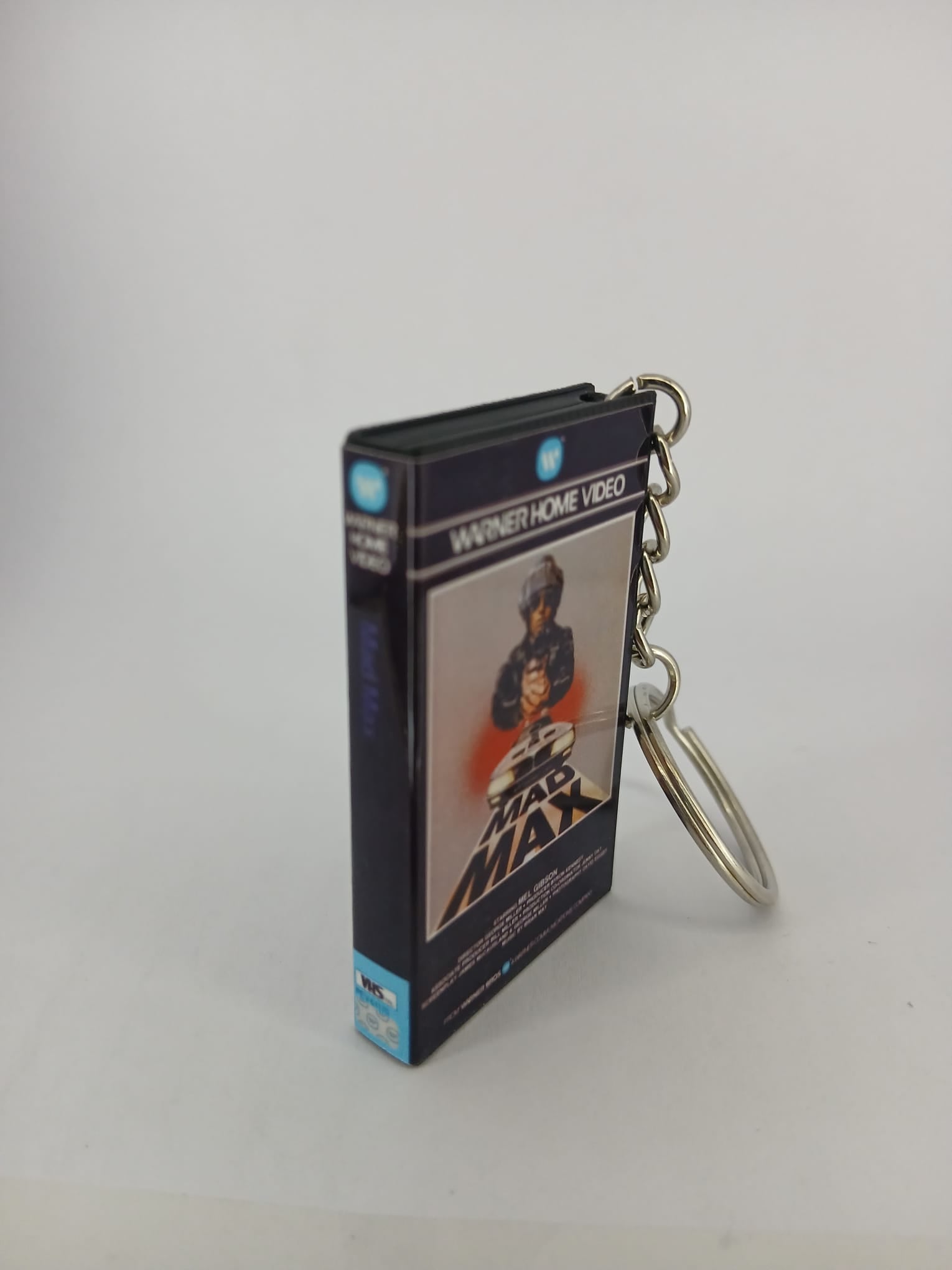 Mad Max VHS keyring — front cover standing with coin for scale