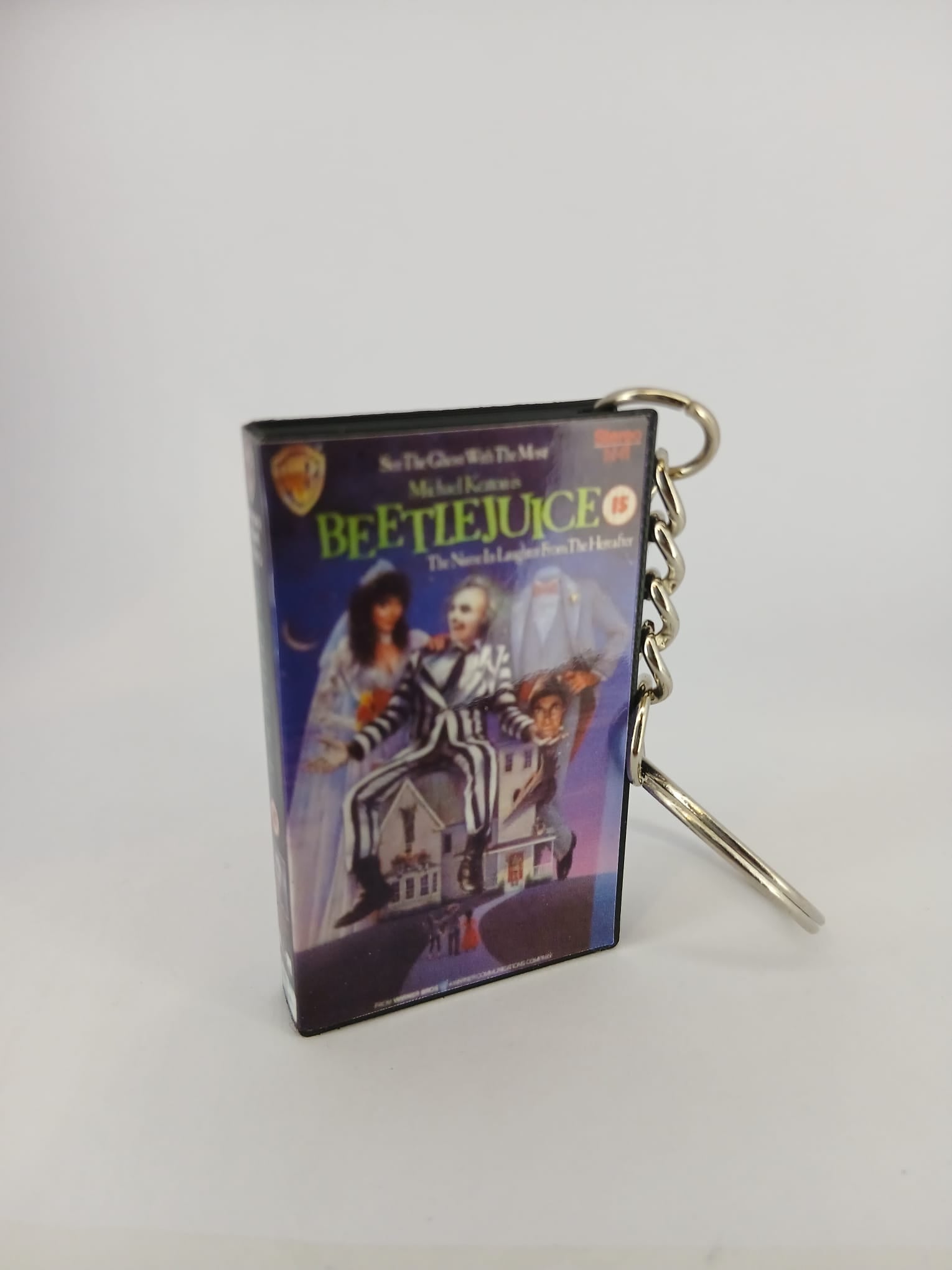 Beetlejuice VHS keyring — front cover standing with coin for scale