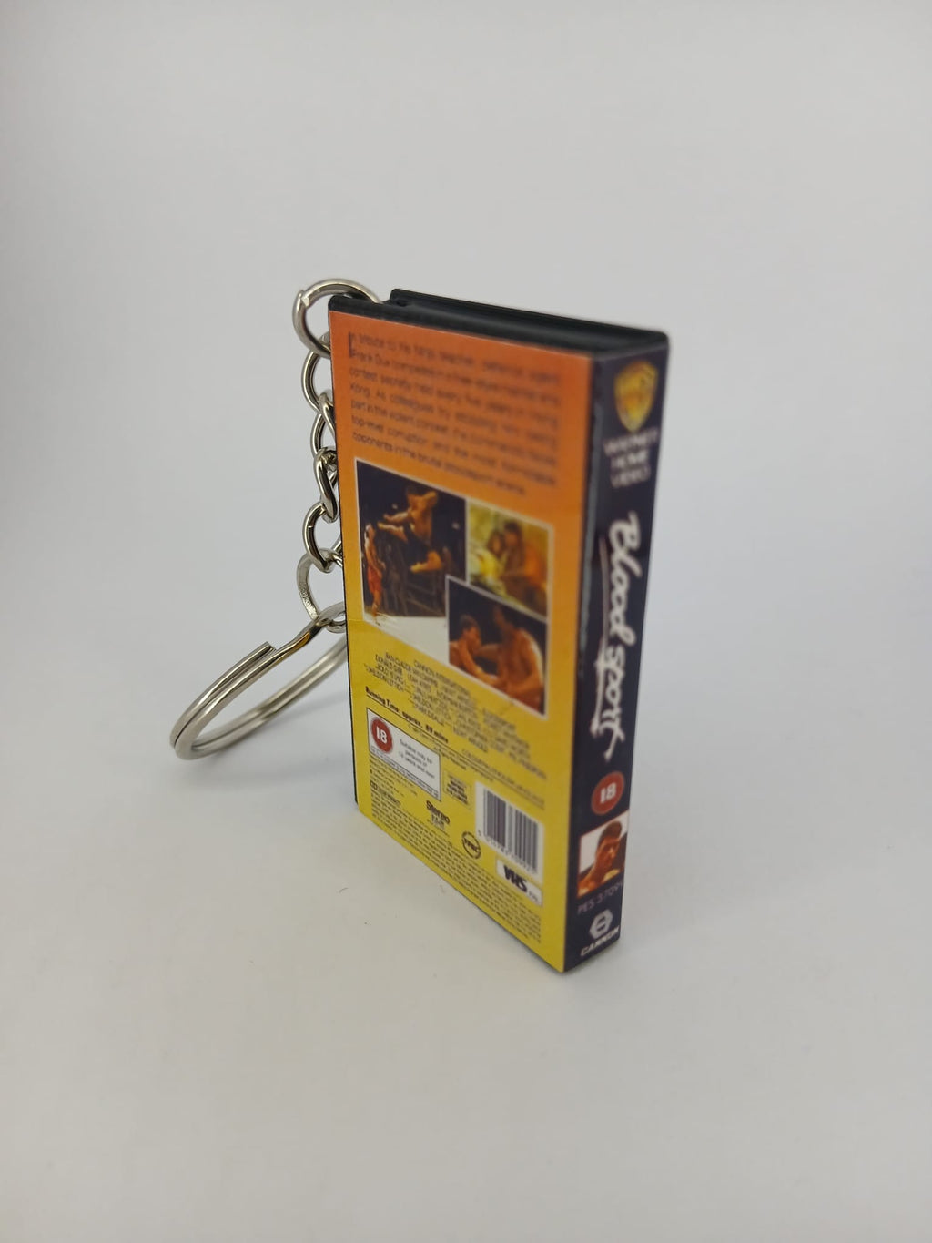Bloodsport VHS keyring — front and spine flat lay angled