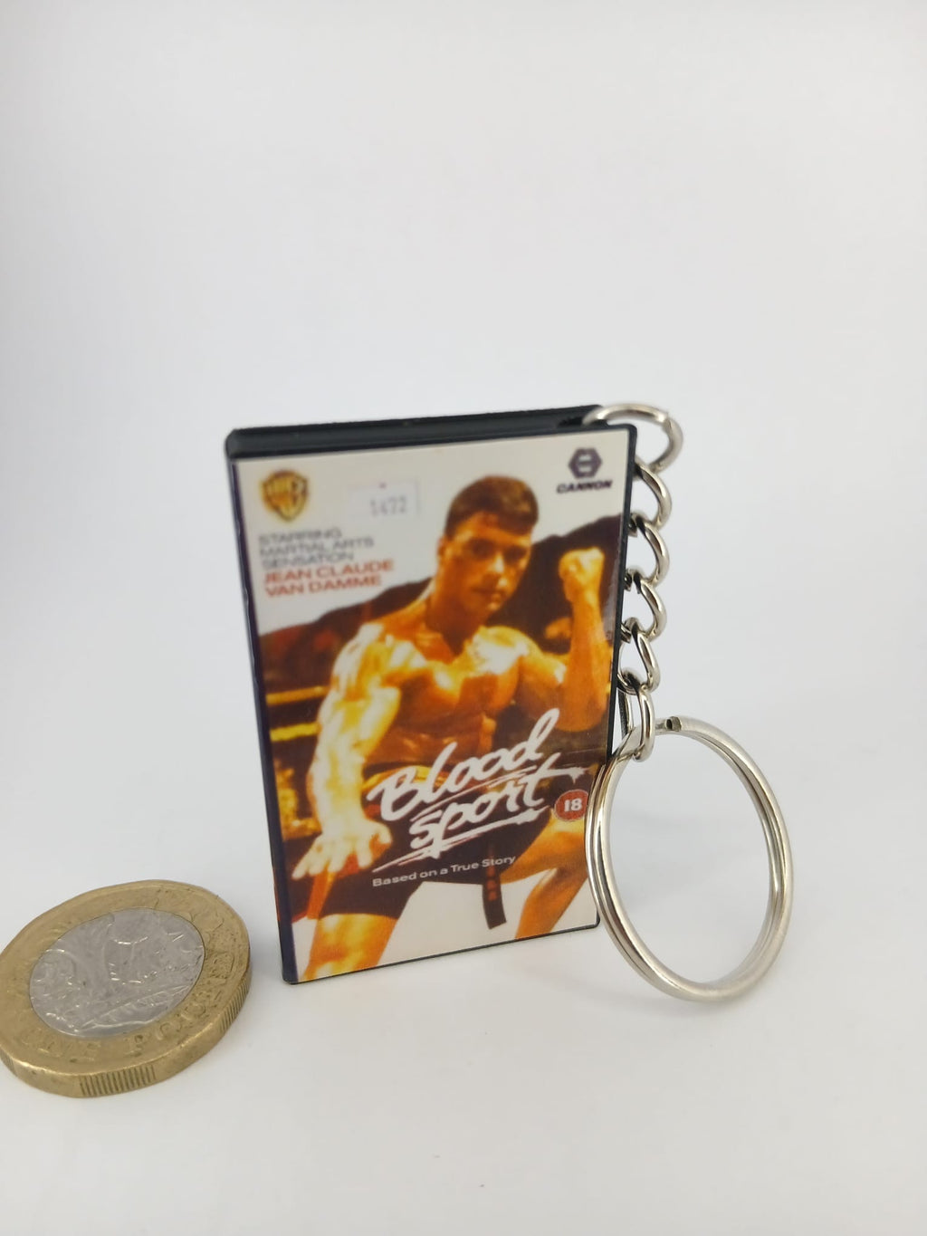 Bloodsport VHS keyring — front cover standing with coin for scale