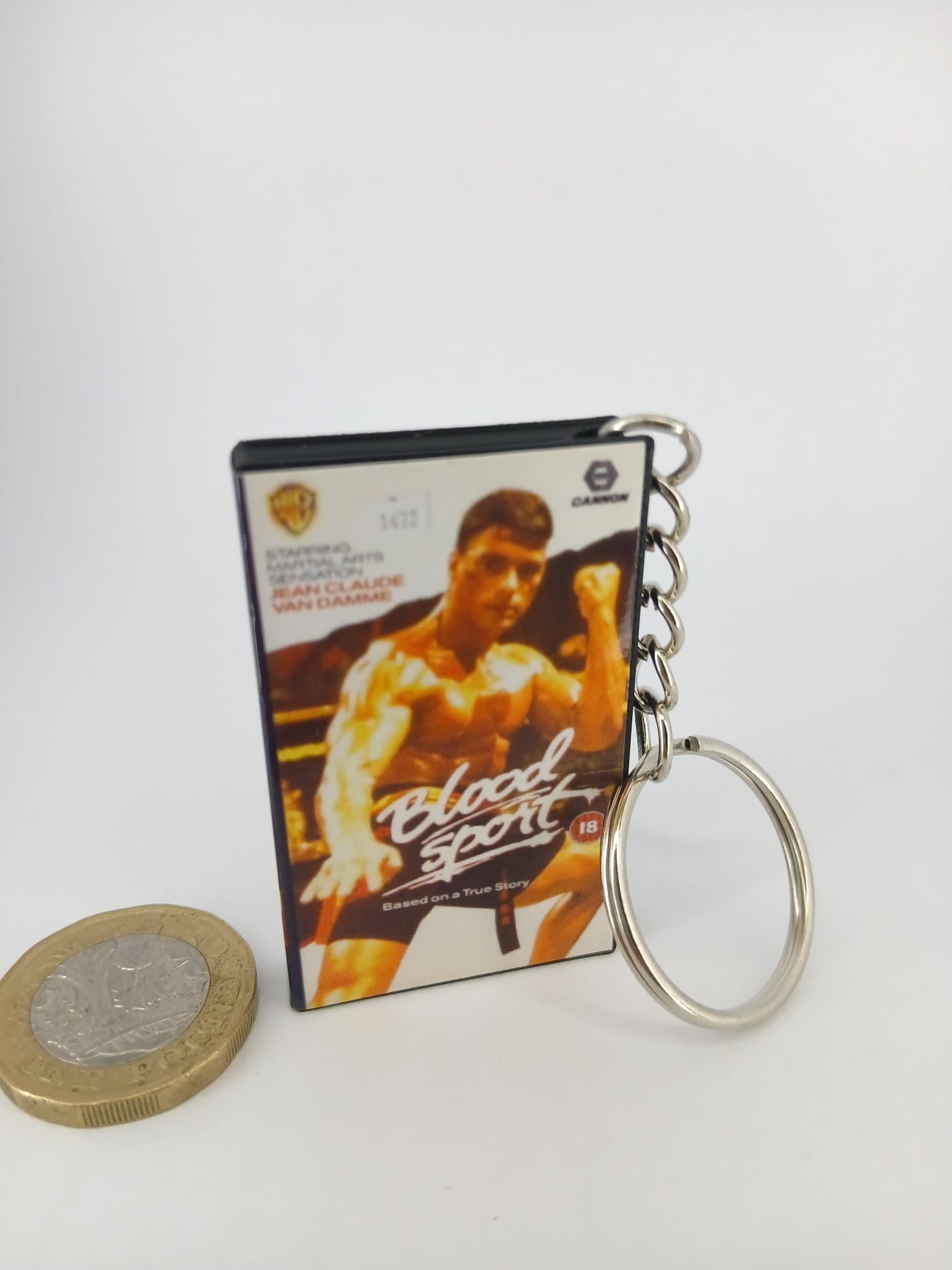 Bloodsport VHS keyring — front cover standing with coin for scale