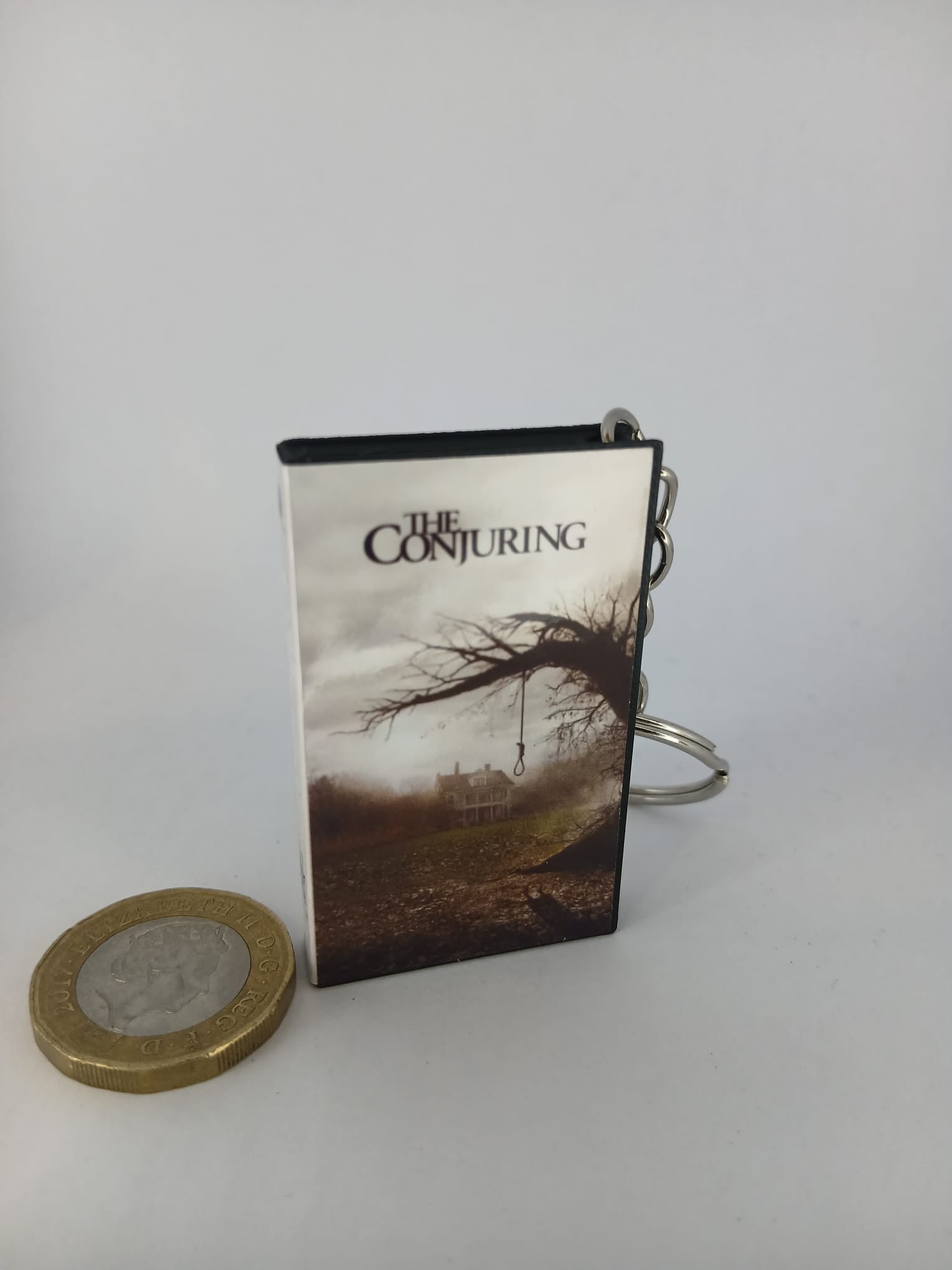 The Conjuring VHS keyring — front cover with 1p coin for scale
