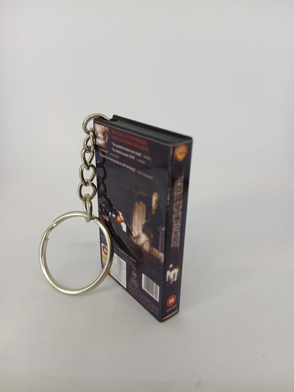 The Exorcist VHS keyring — front cover standing with coin for scale