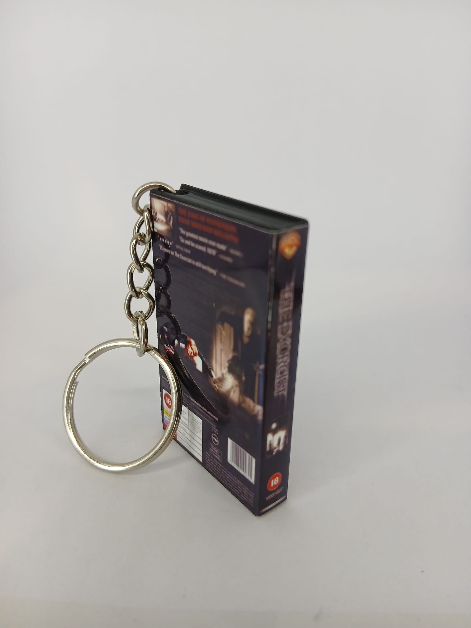 The Exorcist VHS keyring — front cover standing with coin for scale