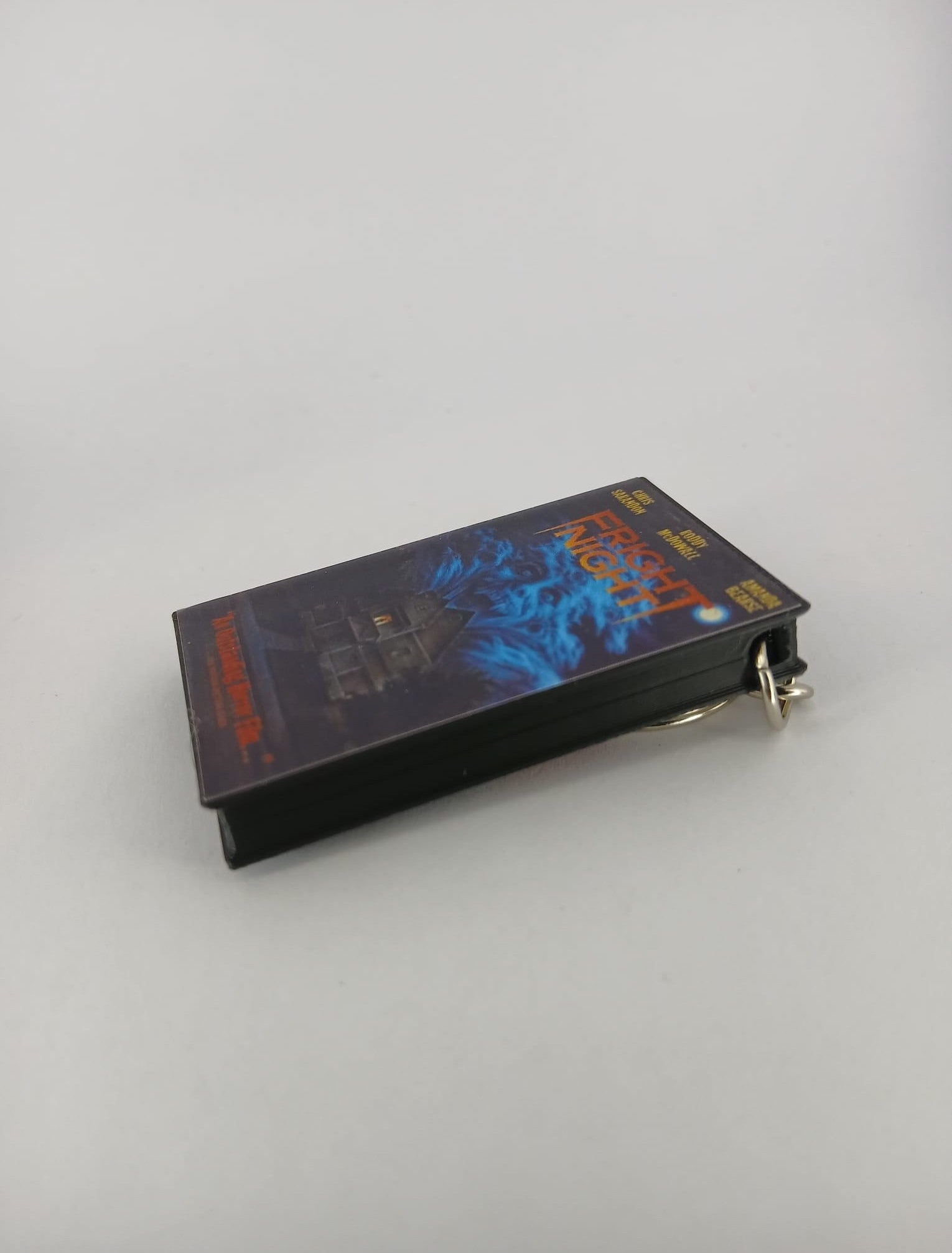 Fright Night VHS keyring — front cover standing angled with coin for scale