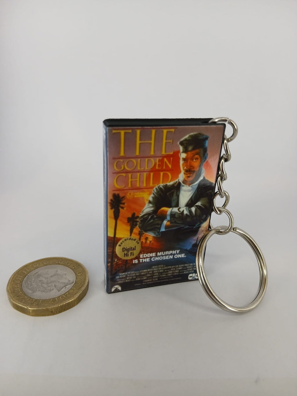 The Golden Child VHS keyring — front cover standing with coin for scale