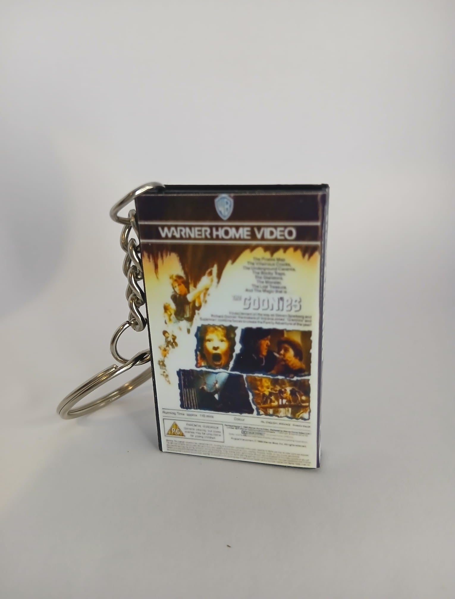The Goonies VHS keyring — front cover standing with coin for scale