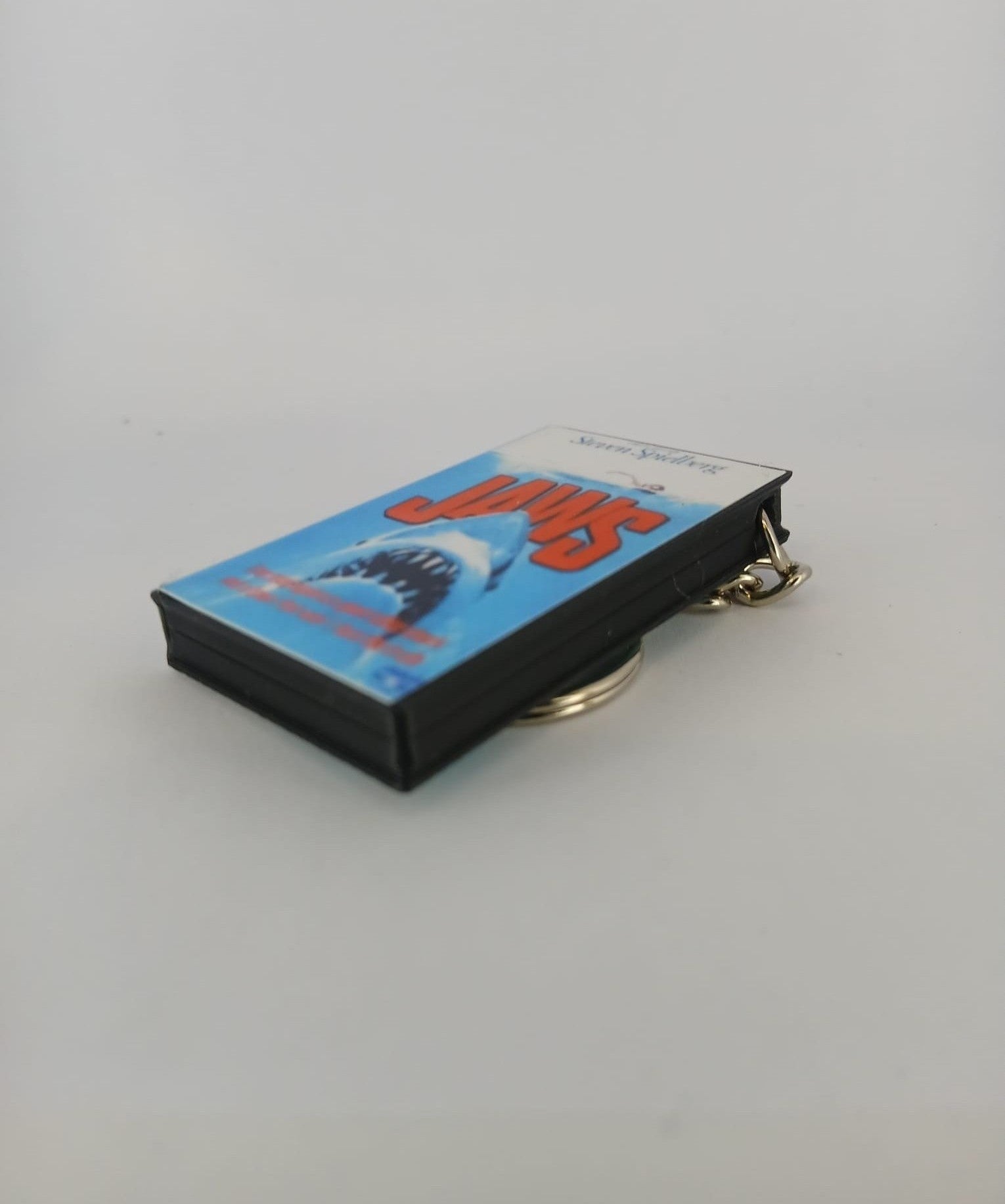 Jaws VHS keyring — front cover standing with coin for scale