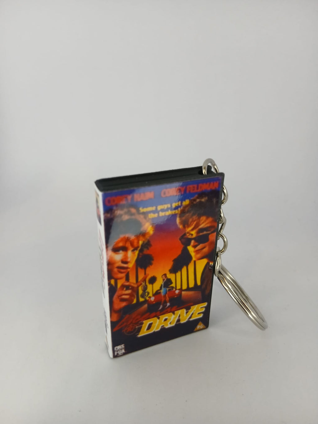 Licence to Drive VHS keyring — front cover with £1 coin for scale