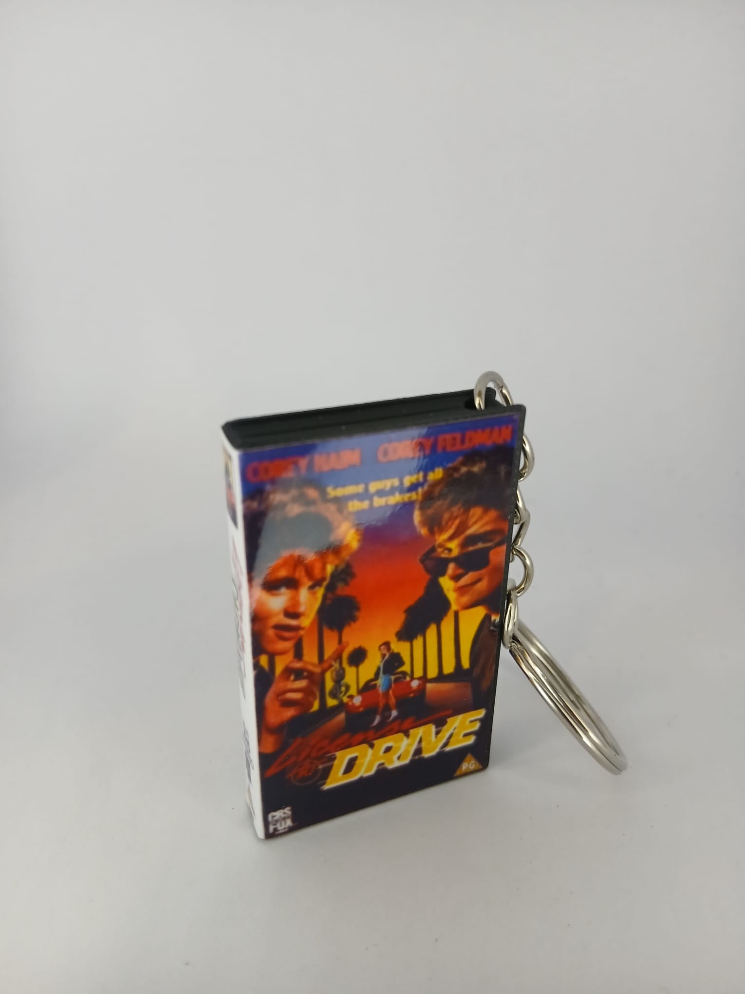 Licence to Drive VHS keyring — front cover with £1 coin for scale