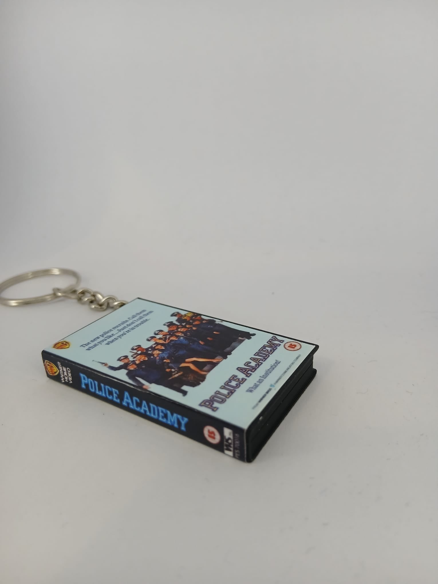 Police Academy VHS keyring — front cover standing angled