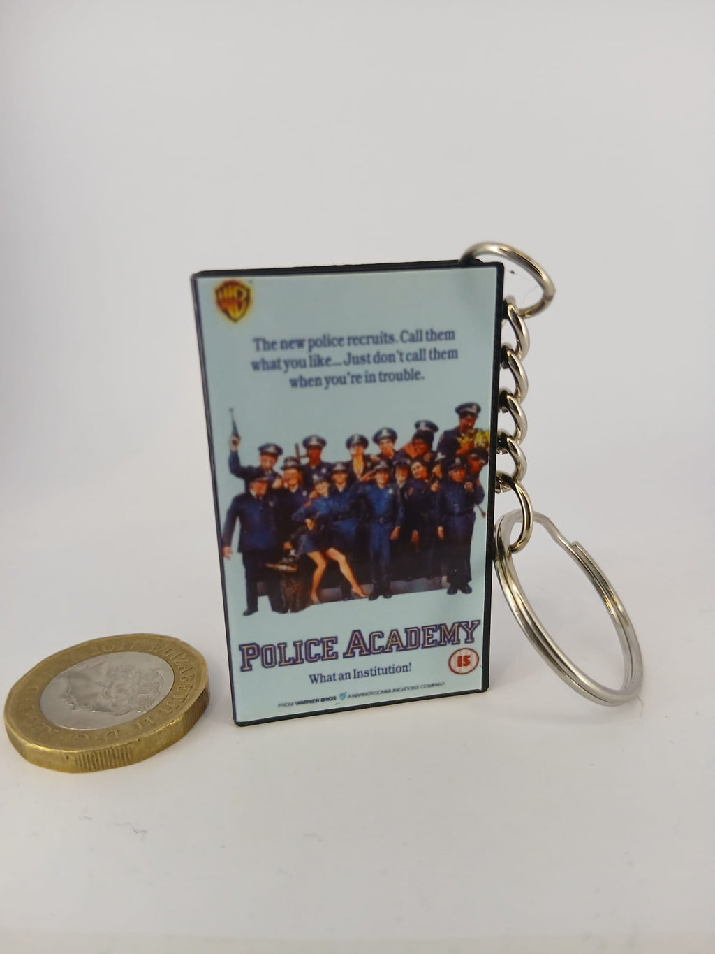 Police Academy VHS keyring — front cover standing with coin for scale