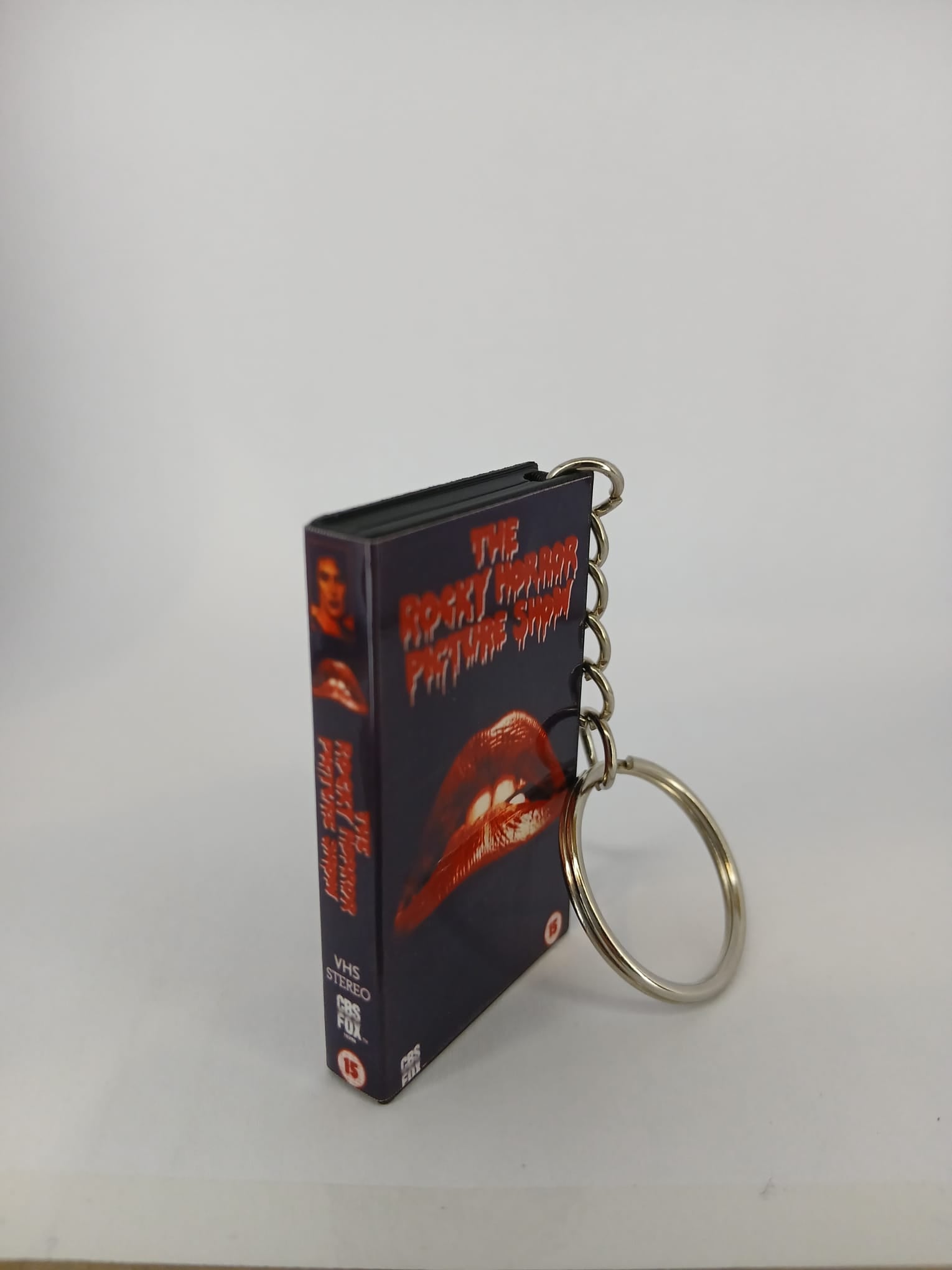 The Rocky Horror Picture Show VHS keyring — front cover standing with coin for scale