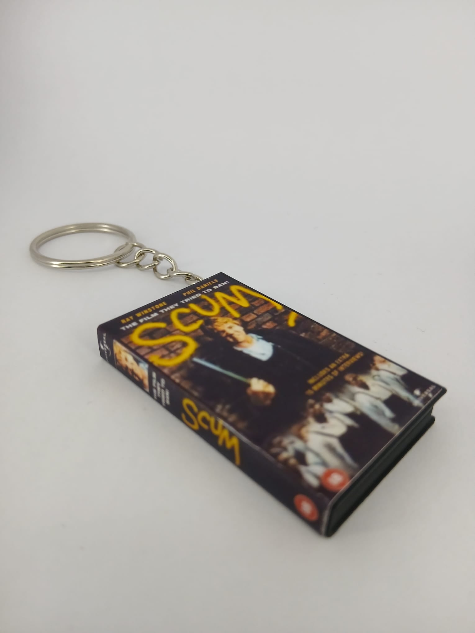 Scum VHS keyring — front cover standing angled