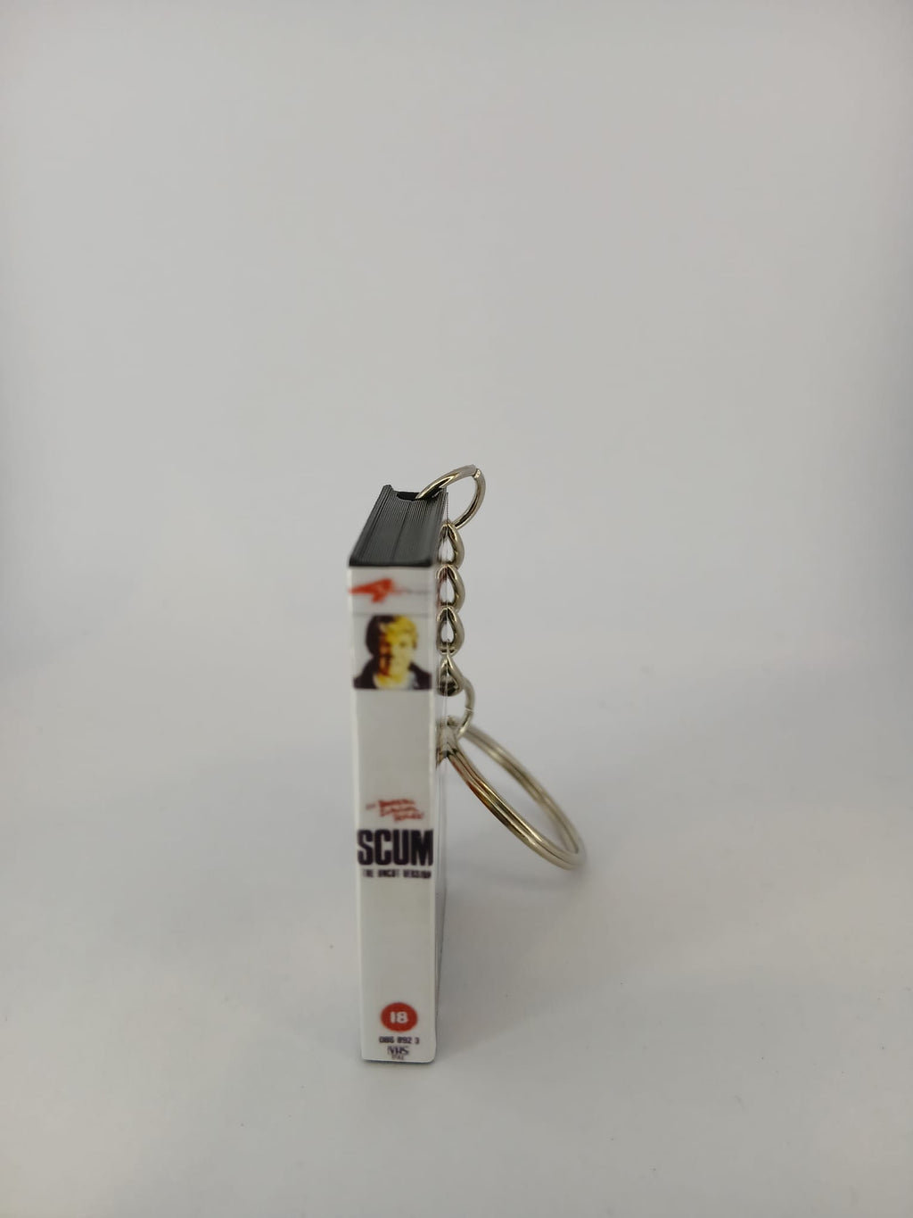 Scum VHS keyring — back cover angled view standing