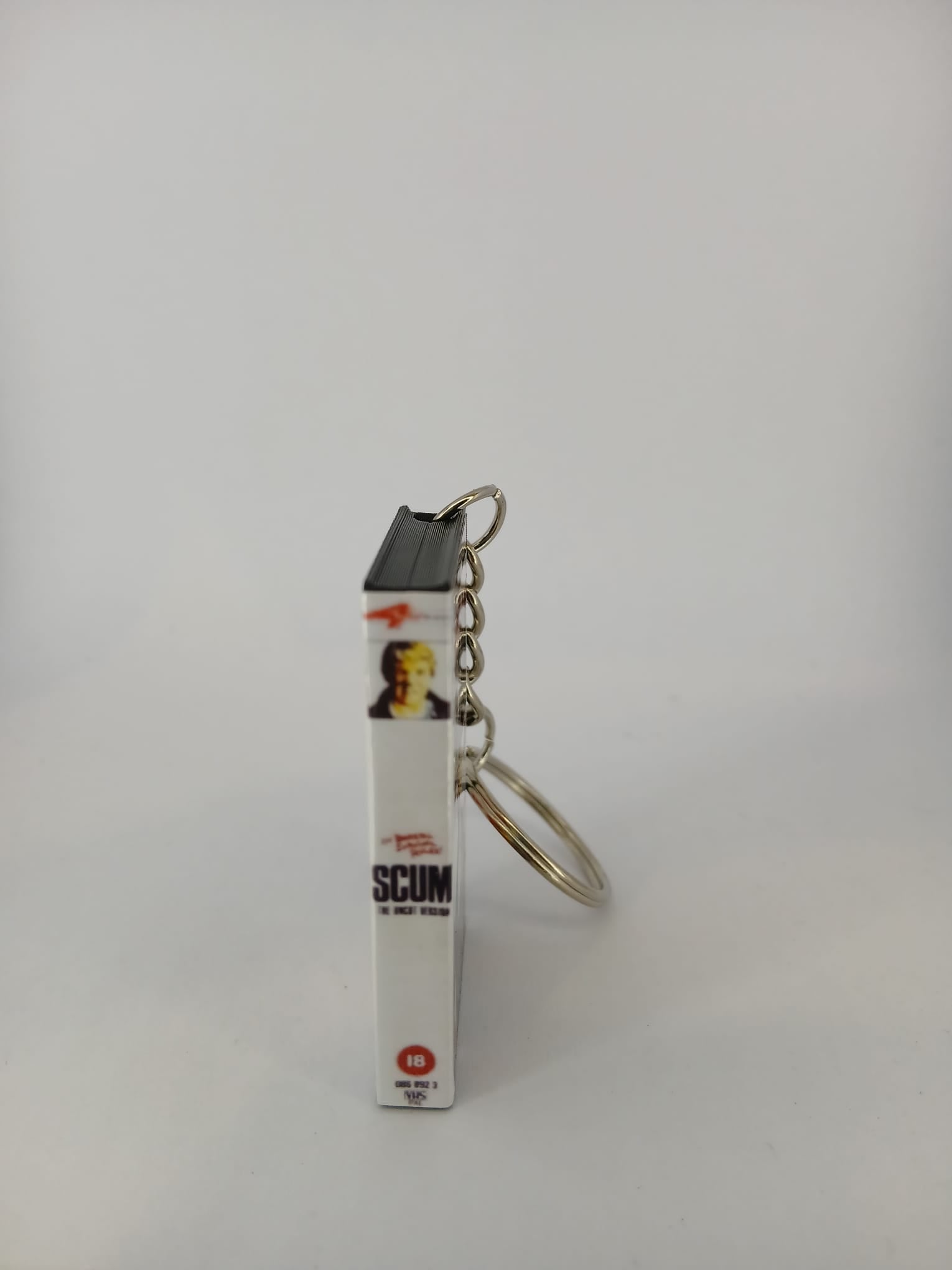 Scum VHS keyring — back cover angled view standing