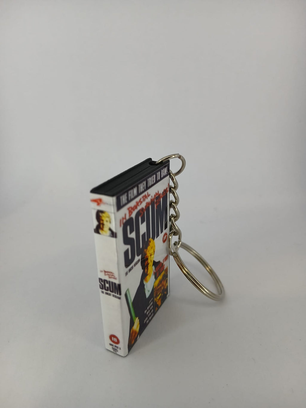 Scum VHS keyring — front cover standing angled 3