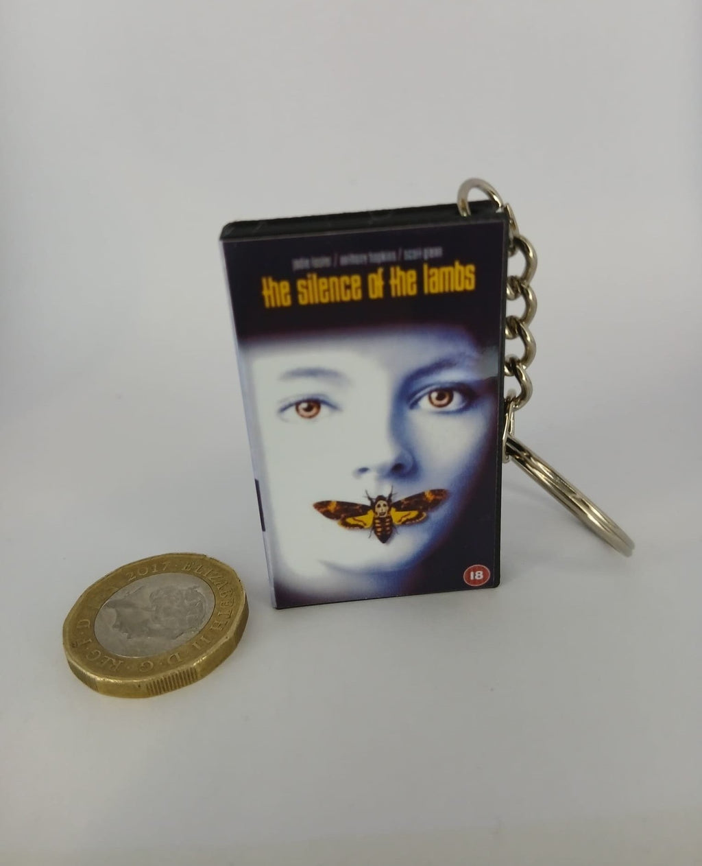 The Silence of the Lambs VHS keyring — front cover standing with coin for scale