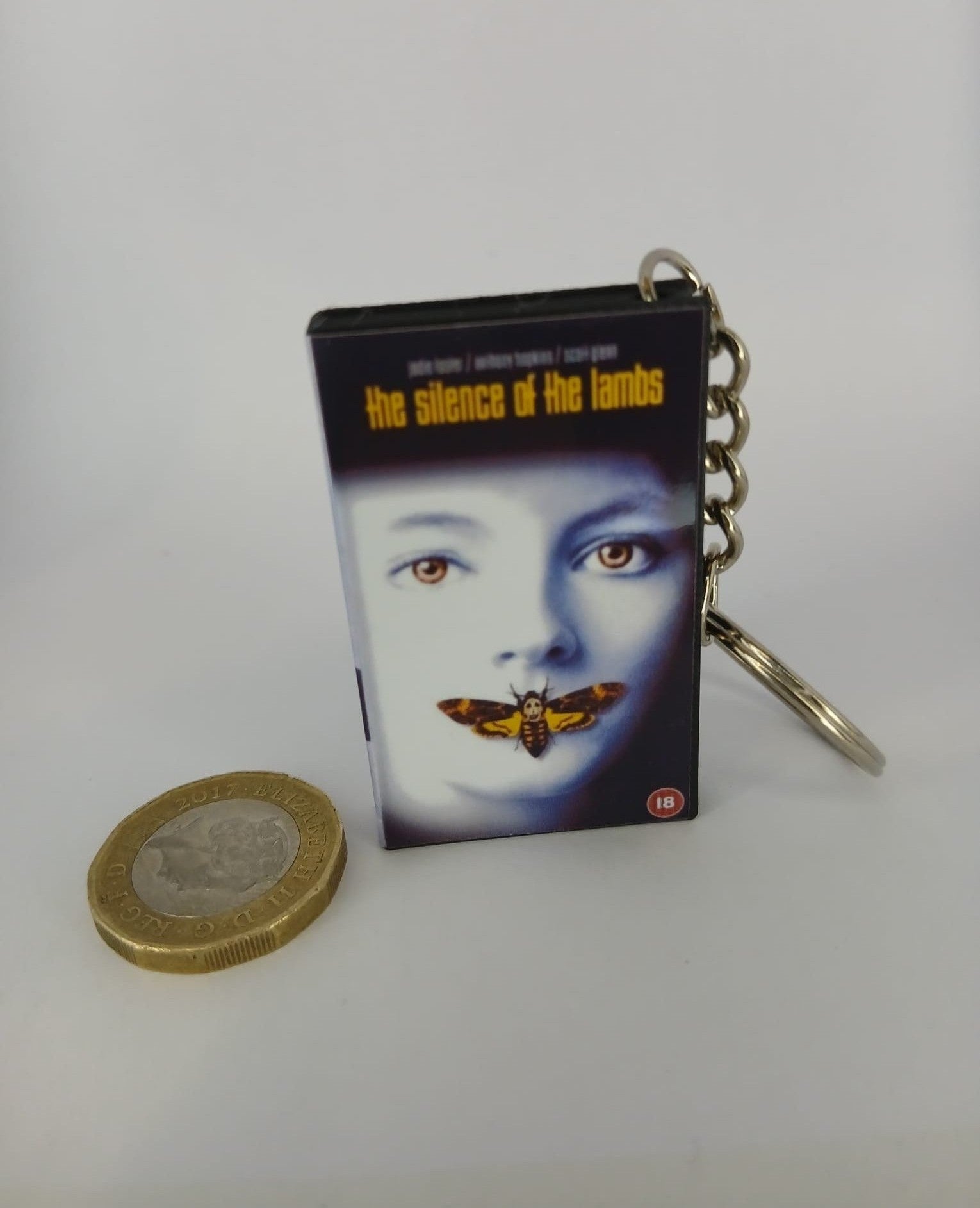 The Silence of the Lambs VHS keyring — front cover standing with coin for scale