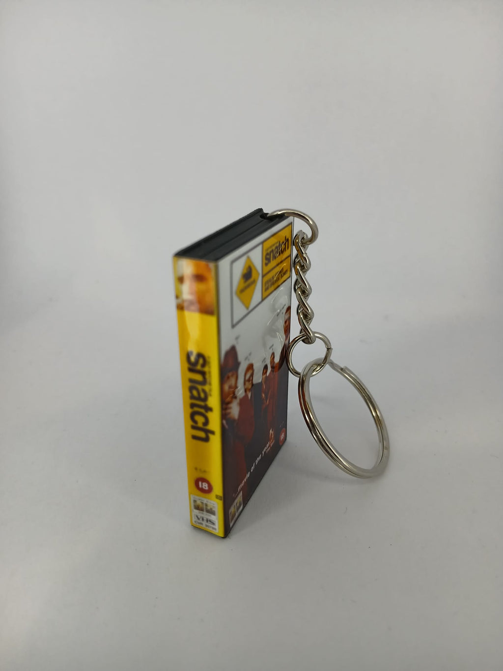 Snatch VHS keyring — front cover standing with coin for scale