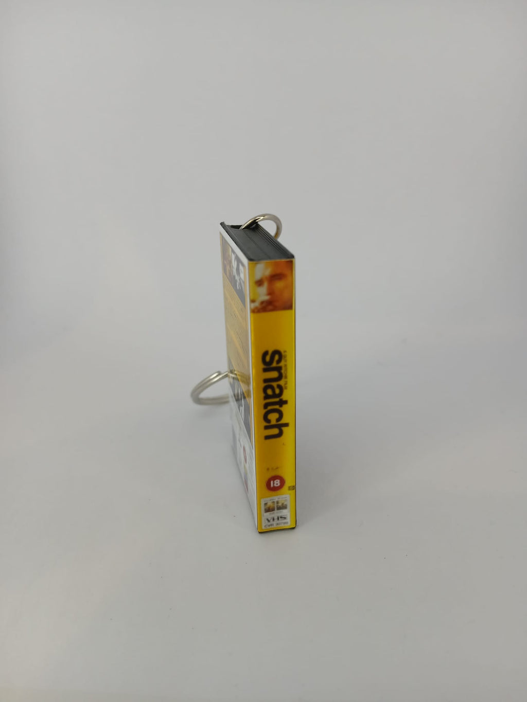 Snatch VHS keyring — back and spine angled view standing