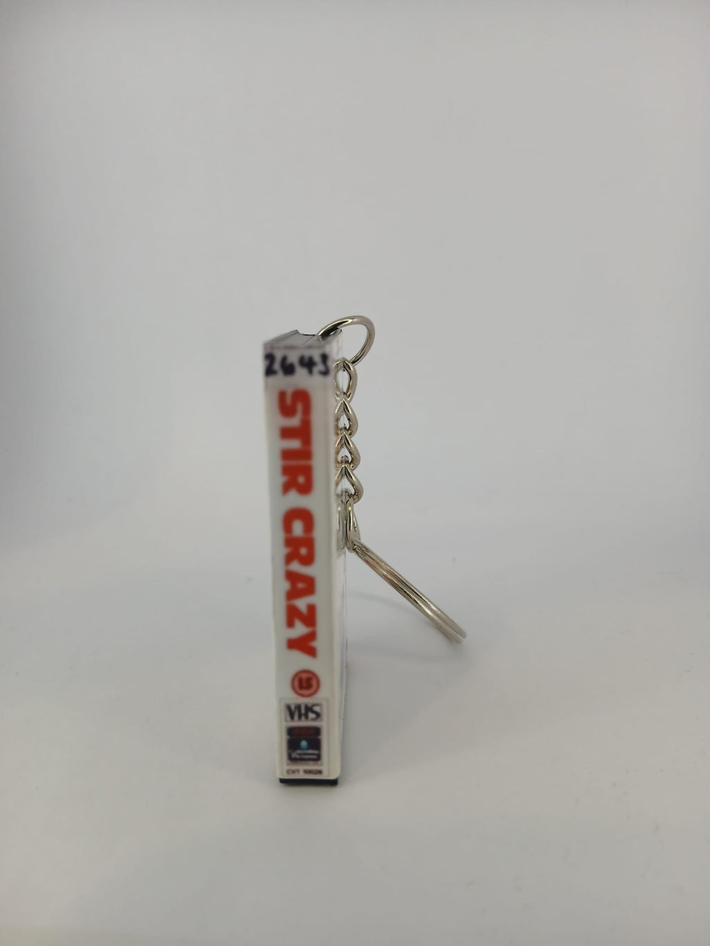 Stir Crazy VHS keyring — front cover standing with coin for scale