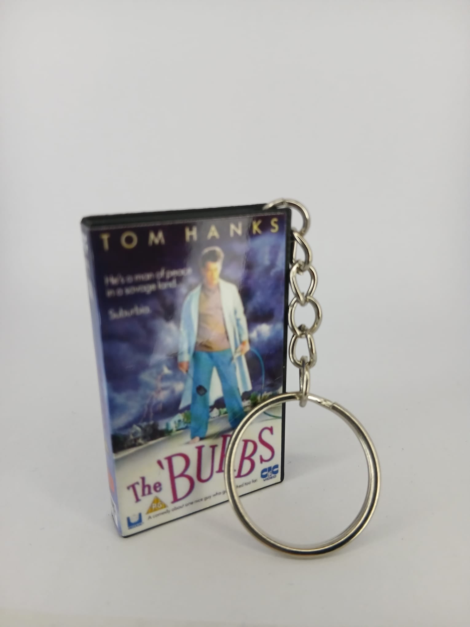 The 'Burbs VHS keyring — back and spine angled view standing