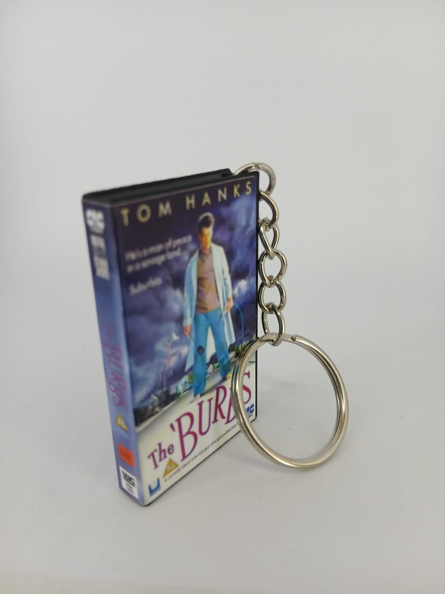 The 'Burbs VHS keyring — front cover standing with coin for scale